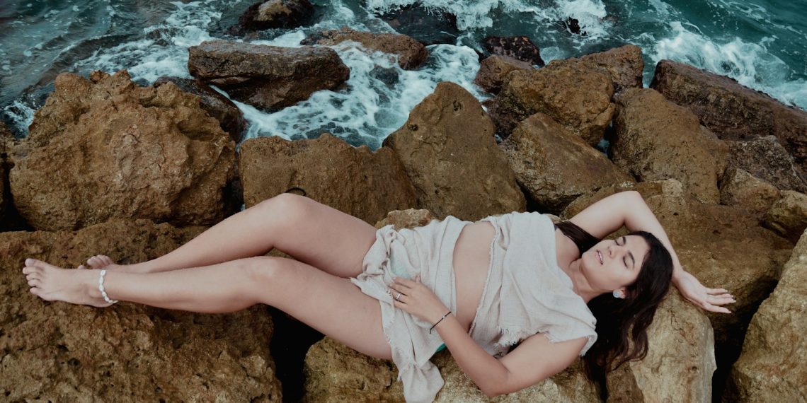 A woman laying on rocks next to the ocean